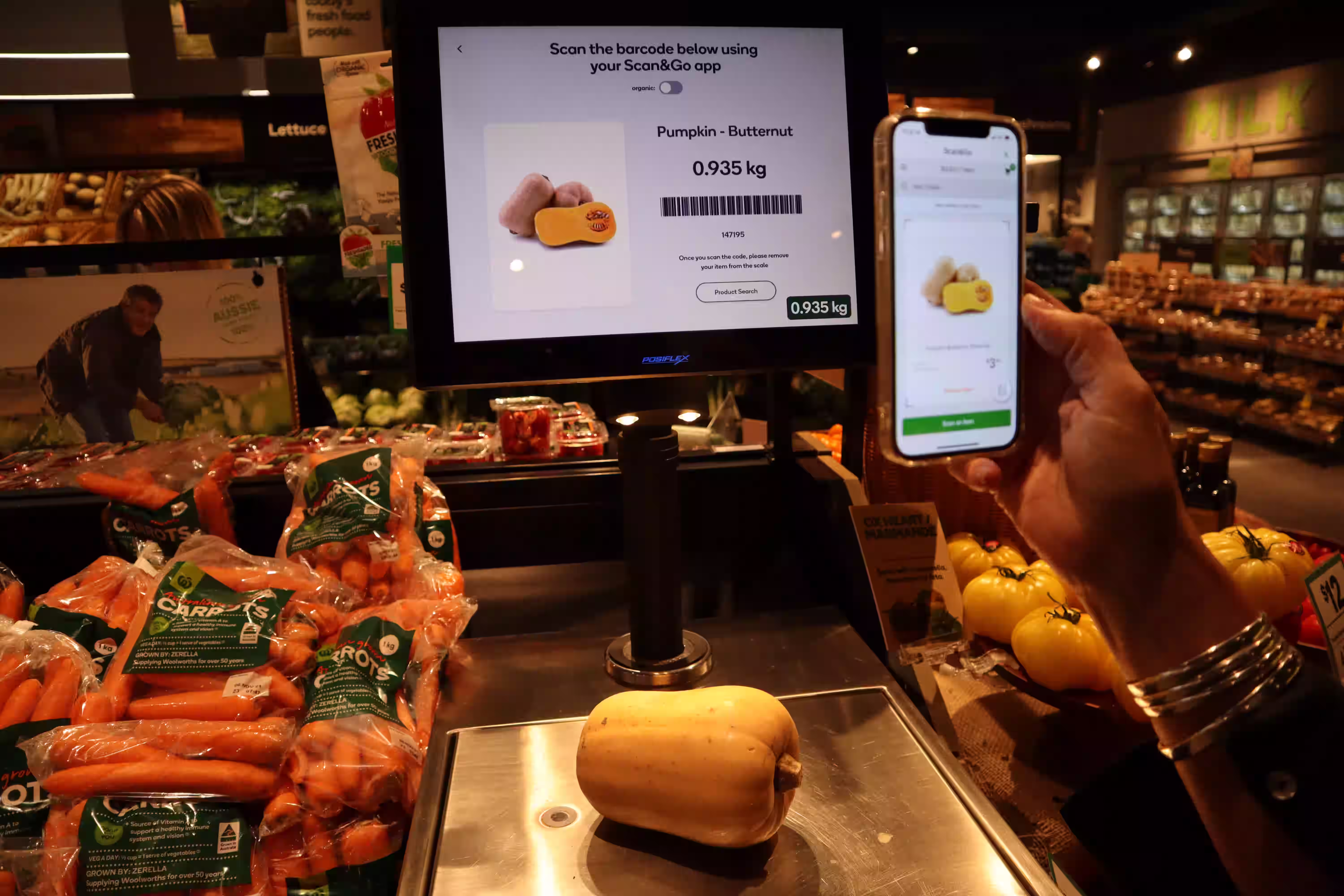 A Tiliter scale in a supermarket produce aisle identifying a butternut pumpkin by weight, with the matching item shown in a shopper's Scan&Go app